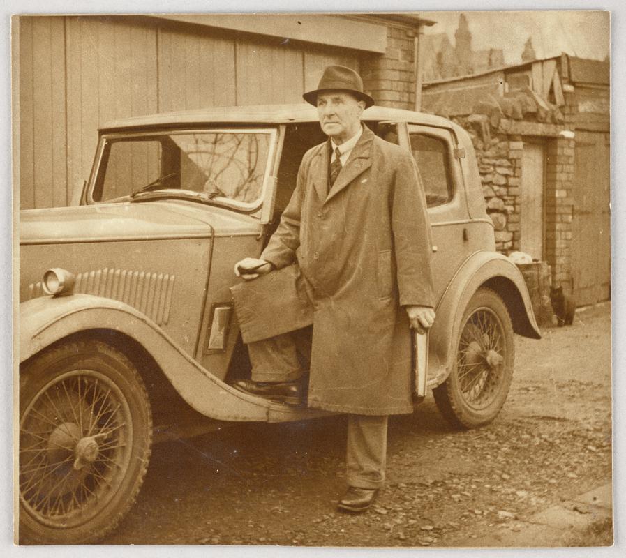View of C.H. Watkins standing next to car.