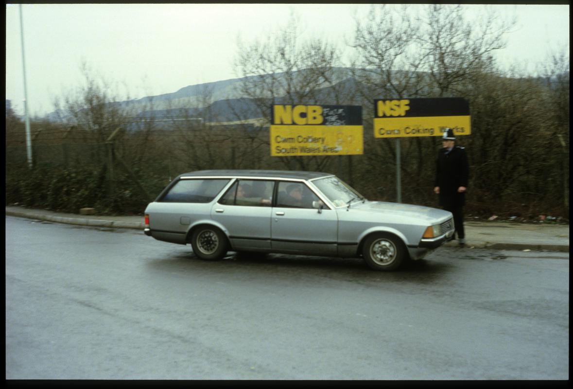 Three 'blackleg' miners being driven home past police guard at Cwm Colliery entrance.