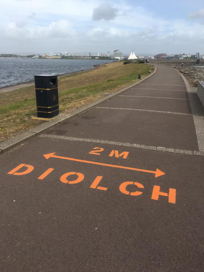 2m social distancing signage painted on the footpath over the Cardiff Bay Barrage. Photo taken the day the painting was being undertaken.