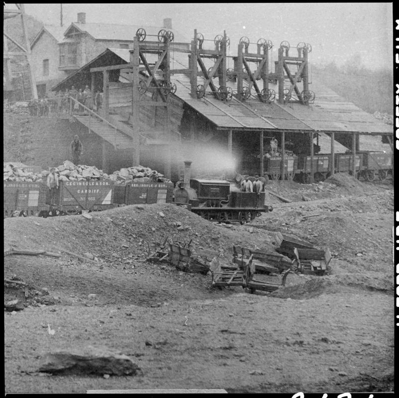 Film negative of a photograph showing a Manning Wardle Locomotive working alongside the screens  at Cymmer Colliery in the 1880s.  In the foreground are the remains of old mine tram waggers.  'Cymmer' is transcribed from original negative bag.