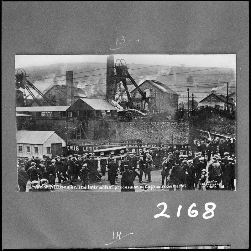 Black and white film negative of a photograph showing the scene at Universal Colliery, Senghenydd following the disaster of 14 October 1913. Caption on photograph reads 'Welsh pit disaster.  The intermittent procession of coffins from the pit'.  'Sen 1913' is transcribed from original negative bag.