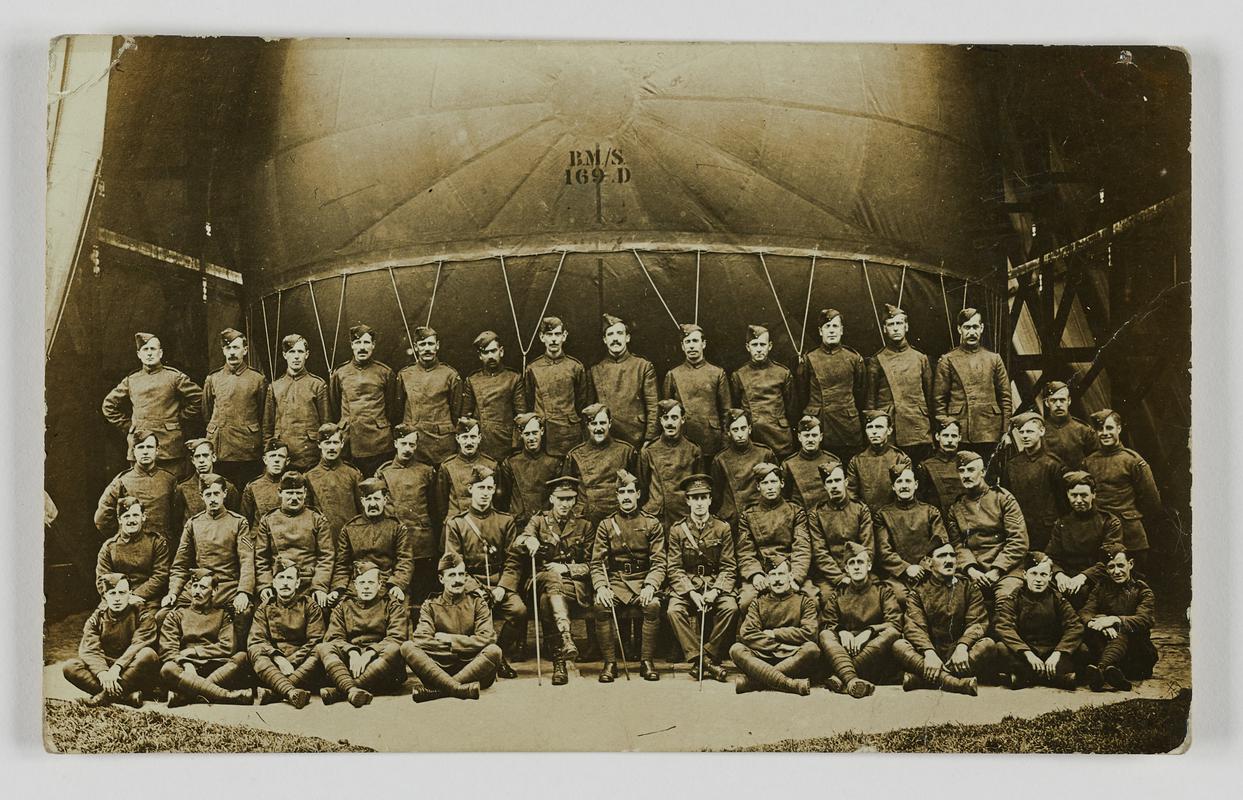 Military personnel posing at nose of airship