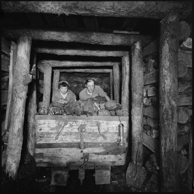 Black and white film negative showing two men at one of the coal faces where visitors to the museum can see a recreation of the working conditions underground, Big Pit Mining Museum.