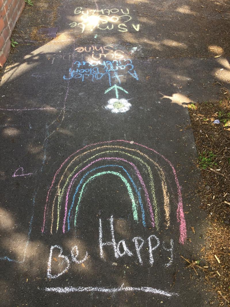 Rainbow and words 'Be Happy' chalked on the pavement of a street in Roath, Cardiff.