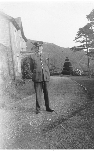 Dinorwig Quarry Hospital. Malcolm Pugh (husband of Vivian Hughes' aunt) outside DQH. Note entrance porch on front of building, and the 'A' incline in the background.