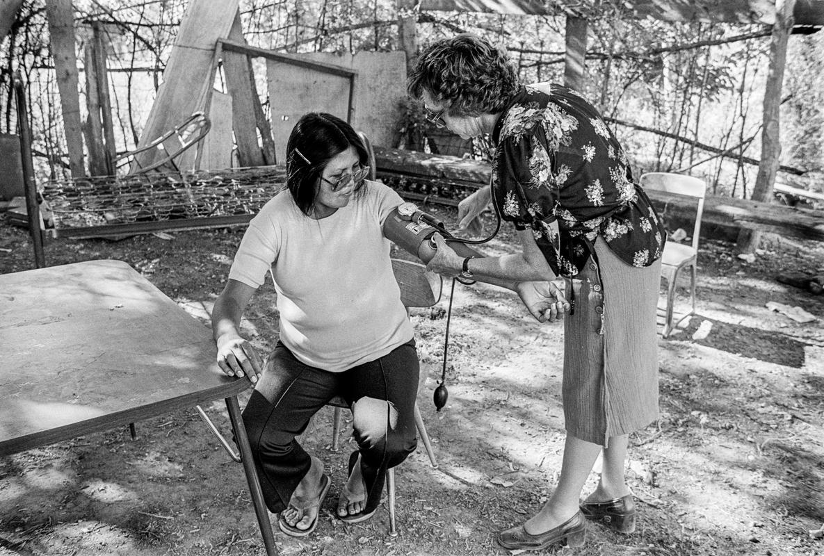 USA. ARIZONA. Doctor from Phoenix checking blood pressure of Apache woman on the reservation. Done in the open as they do not like strangers coming into their houses. 1980.