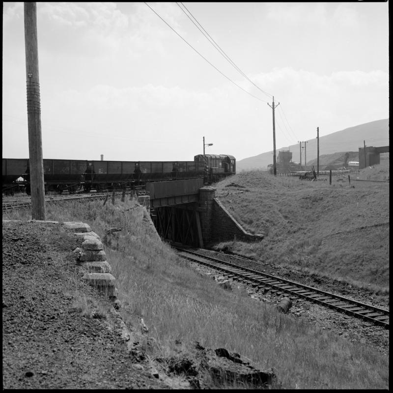 Black and white film negative showing a locomotive pulling coal wagons at Big Pit Colliery.