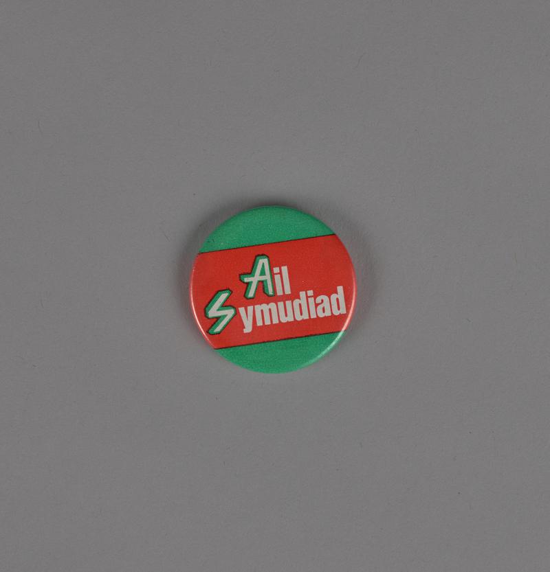 Badge 'Ail Symudiad' on green and red background for BBC children's programme