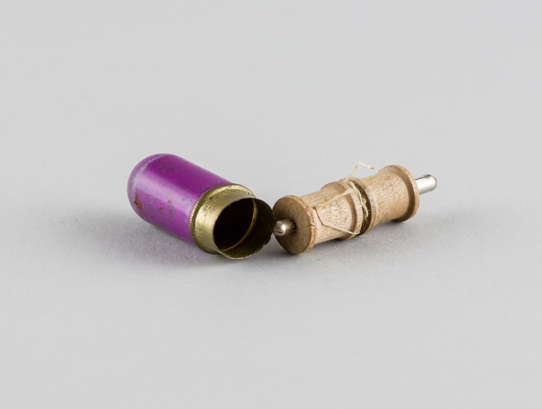 Two bobbins inside a plastic coated brass container.
