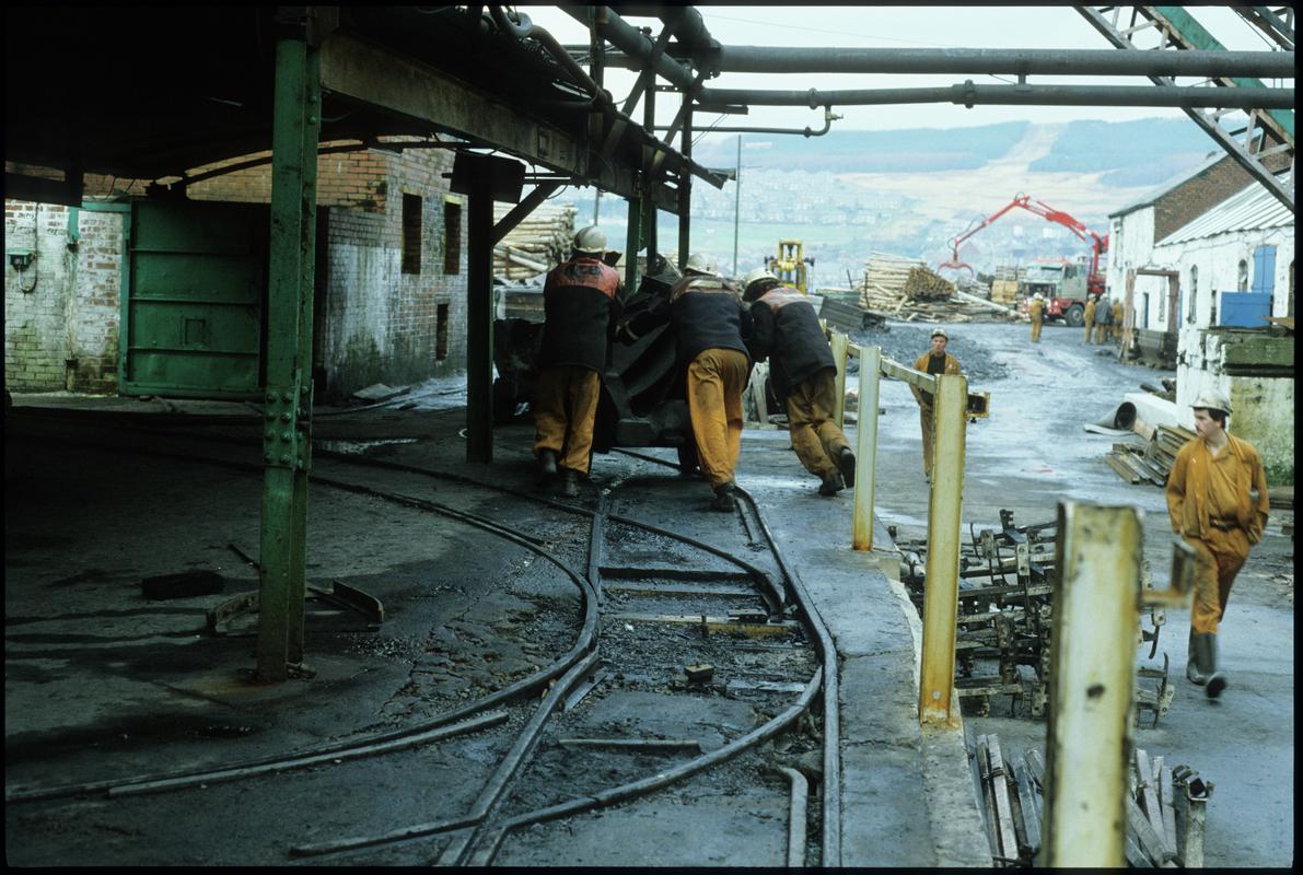 Colour film slide showing men pushing drams at the pit circuit, Coegnant Colliery, 25 November 1981.