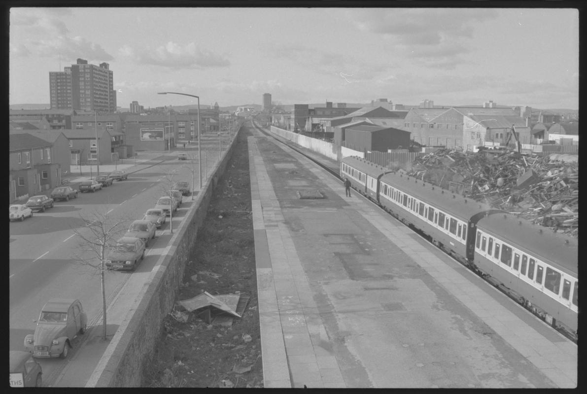 View from Bute Road Station, looking north, with train in station and traffic moving along Bute Street.