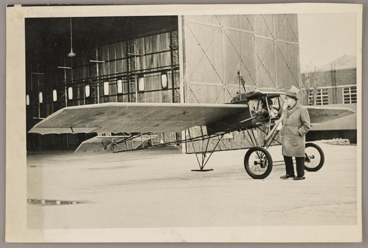 Photograph of Watkins monoplane ouside a hanger at St. Athan in 1964. C.H. Watkins standing at side.