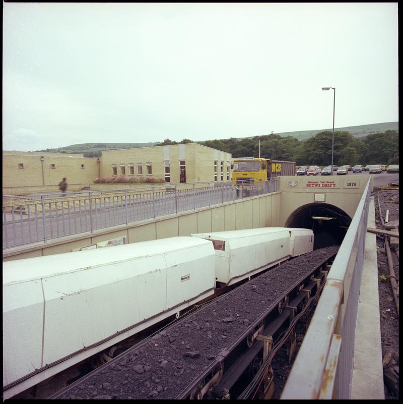 Colour film negative showing the entrance to the mine with man riding cars and conveyor, Betws Mine 10 June 1982.  '10 Jun 1982' is transcribed from original negative bag.  Appears to be identical to 2009.3/2179.