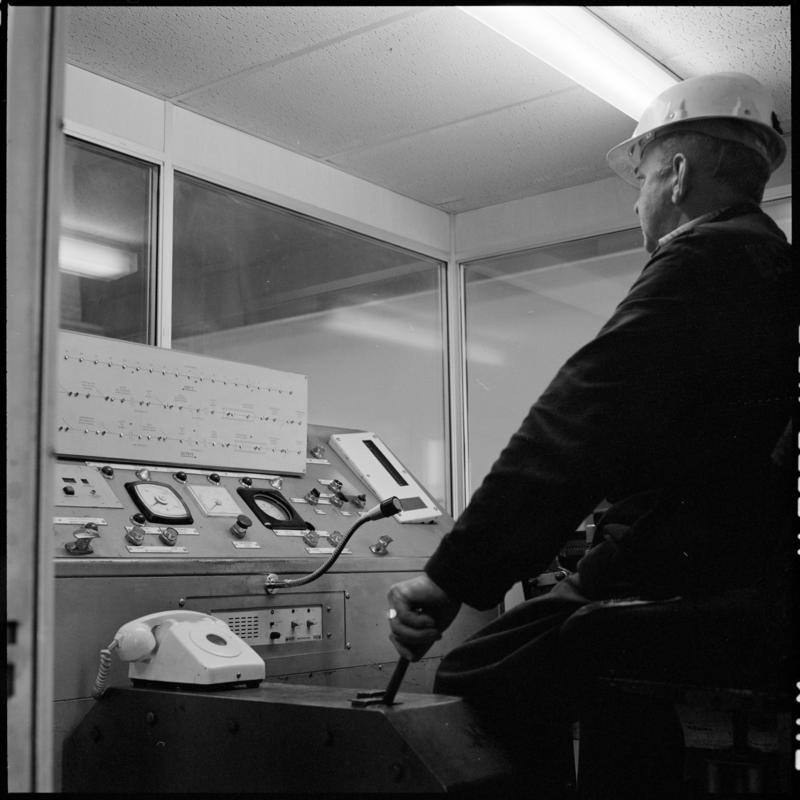 Black and white film negative showing a man operating controls, Betws Mine.  'Betws' is transcribed from original negative bag.