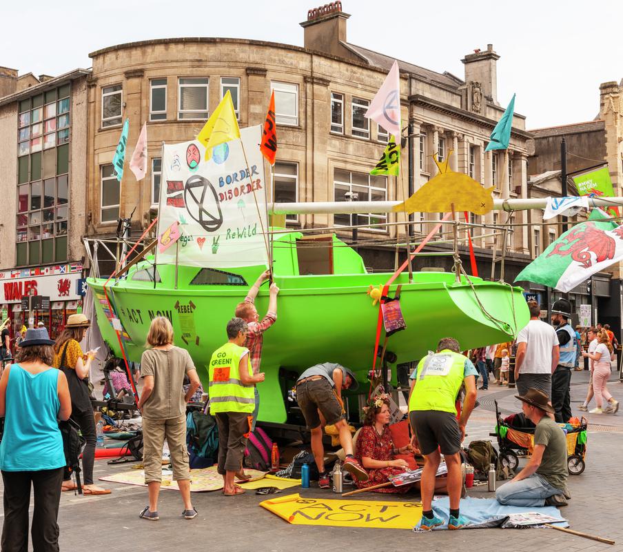 Extinction Rebellion Protest in Cardiff, blocking the road outside Cardiff Castle with a green yacht and Protest Slogans.