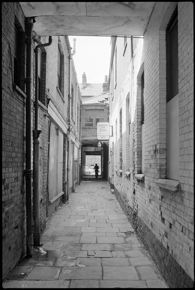 Alleyway from West Bute Street to Mount Stuart Square, Butetown, with broken 'Dowlais Inn' sign.