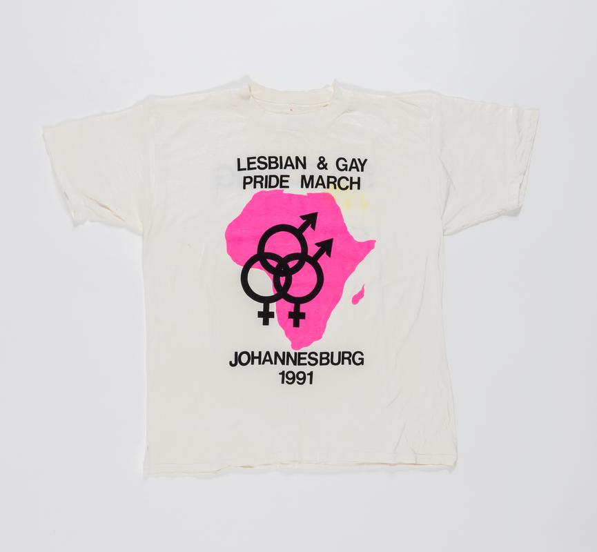 White t-shirt with double womens symbol within a pink outline of Africa, and words 'Lesbian & Gay Pride March Johannesburg 1991' on the front, and 'Marching for Equality' on the back.