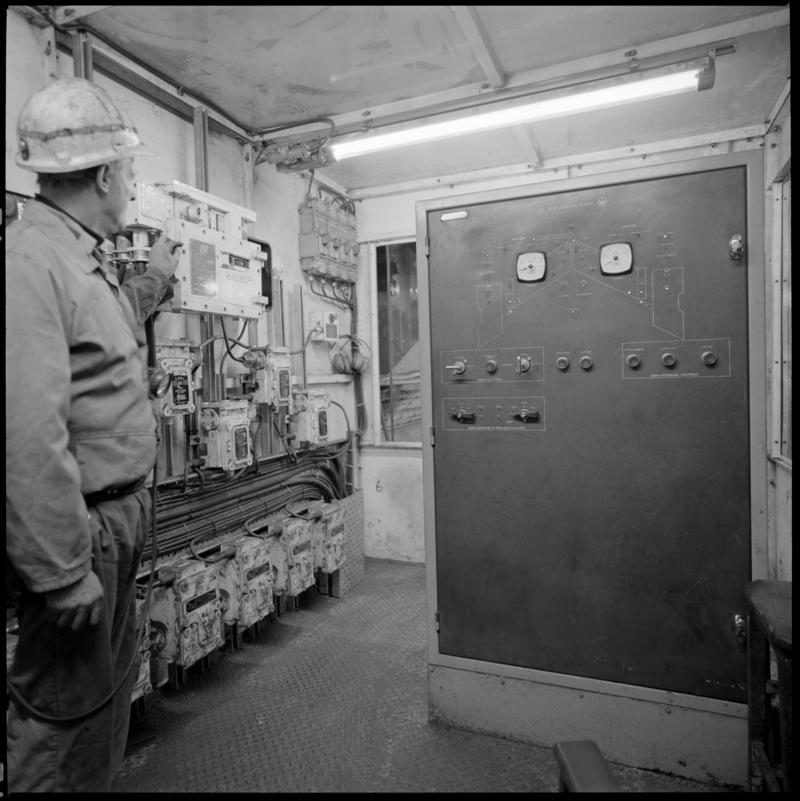 Black and white film negative showing man operating controls, Lady Windsor Colliery.