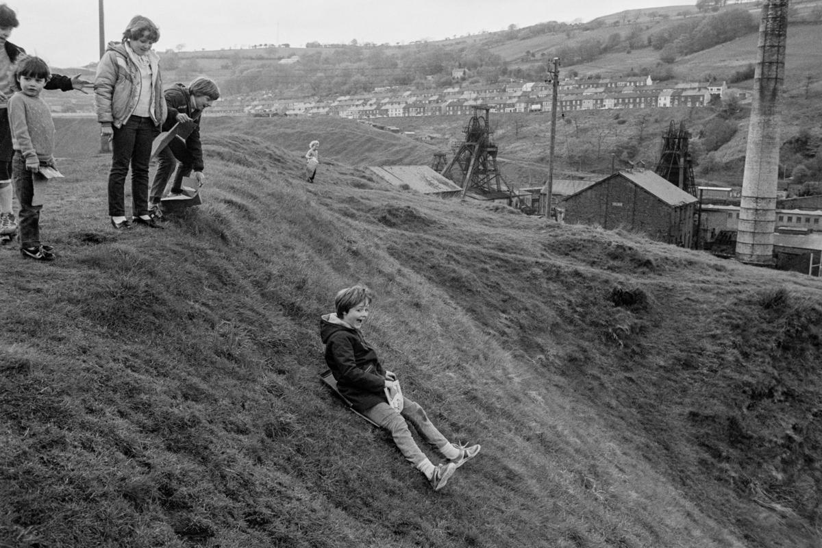 GB. WALES. Porth. Coal tip sledge fun. 1983