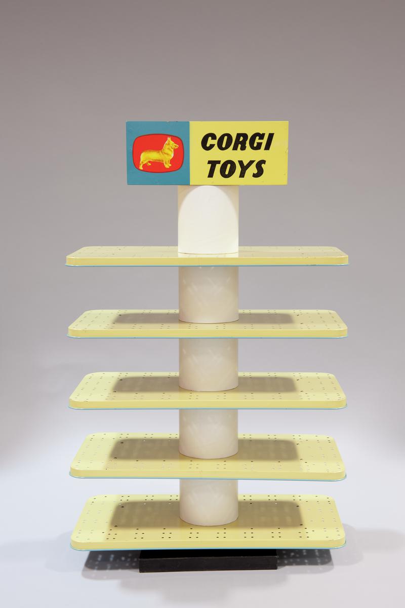 Corgi Toys shop display stand. Central revolving pole with five blue and cream tinplate shelves and 'Corgi Toys' with dog symbol surrounding the hidden handle.