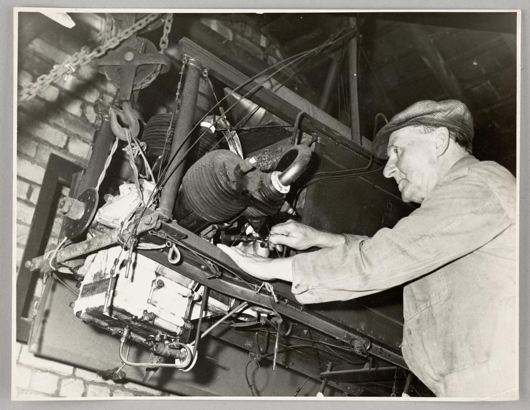 View of C.H. Watkins working on engine in aeroplane.