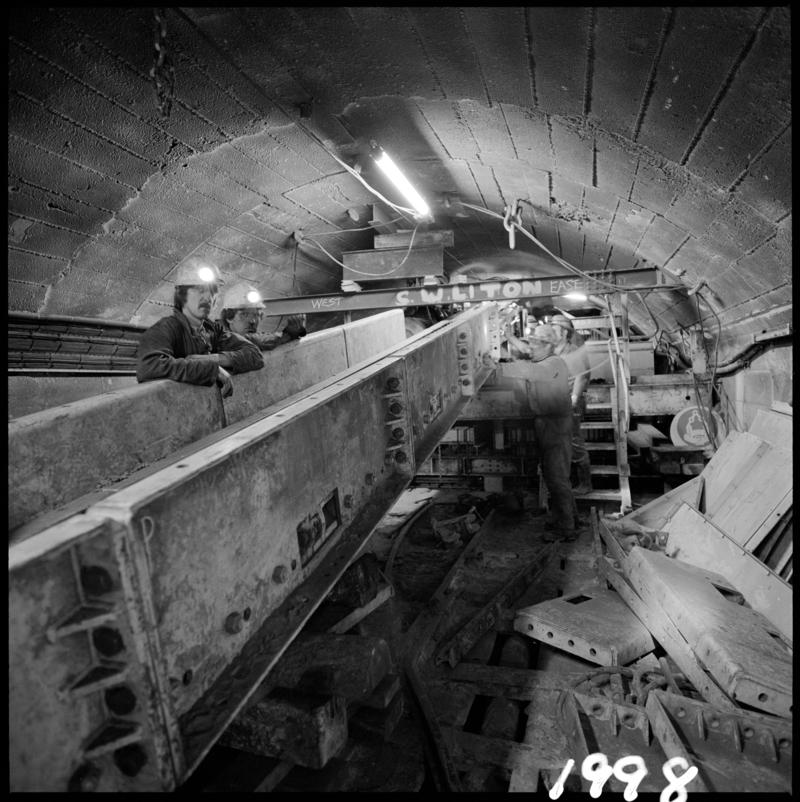 Black and white film negative showing fitters at work in the reconstructed pit bottom, prior to the fitting of the skips, Lady Windsor Colliery.