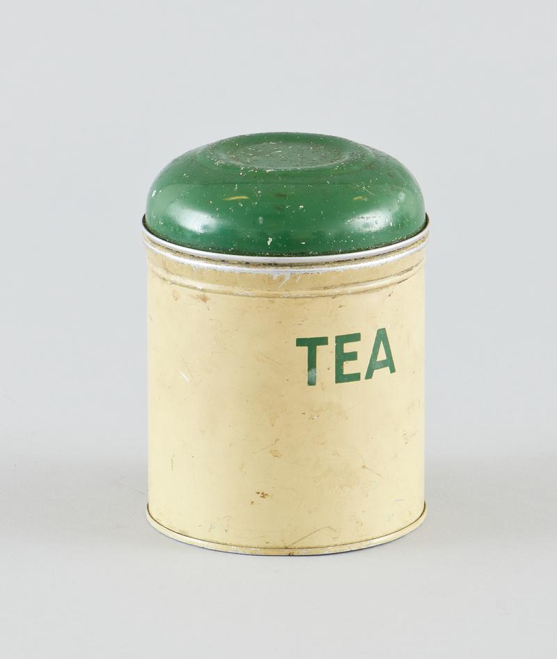 Round tin cream tea caddy with TEA painted onto side in green, with green lid. Paint scratched from surface around rim.