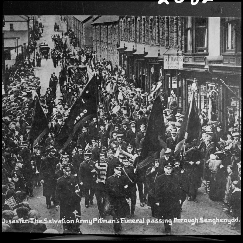 Black and white film negative of a photograph showing a funeral procession passing through Senghenydd.  Caption on photograph reads 'The Salvation Army Pitman's funeral passing through Senghenydd'.