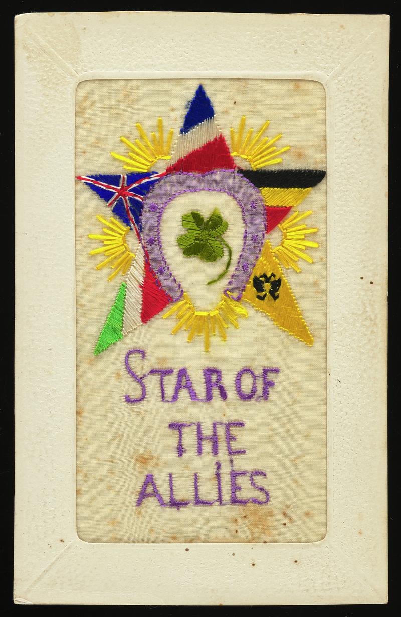Embroidered silk postcard inscribed Star of the Allies. Sent from France by either Gordon Hobbs or Tom Hardiman during First World War. Undated. Embroidered with lilac horseshoe and four leaf clover surrounded by a five-pointed star of flags. No message on back.