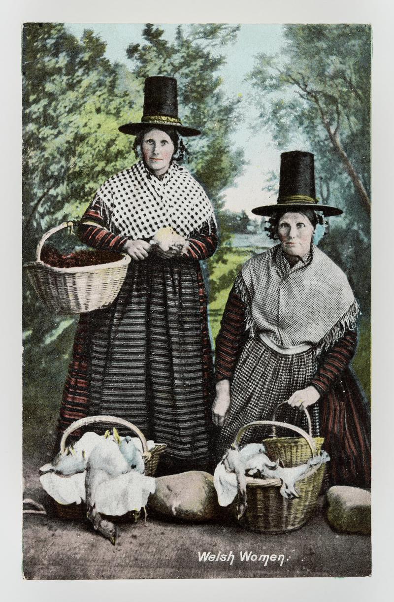 2 Welsh women with baskets of produce including poultry.