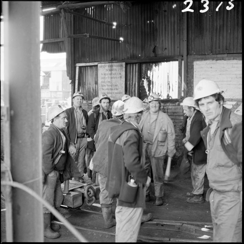 Black and white film negative showing a group of miners on the surface, Morlais Colliery 13 May 1981.  'Morlais 13/5/81' is transcribed from original negative bag.