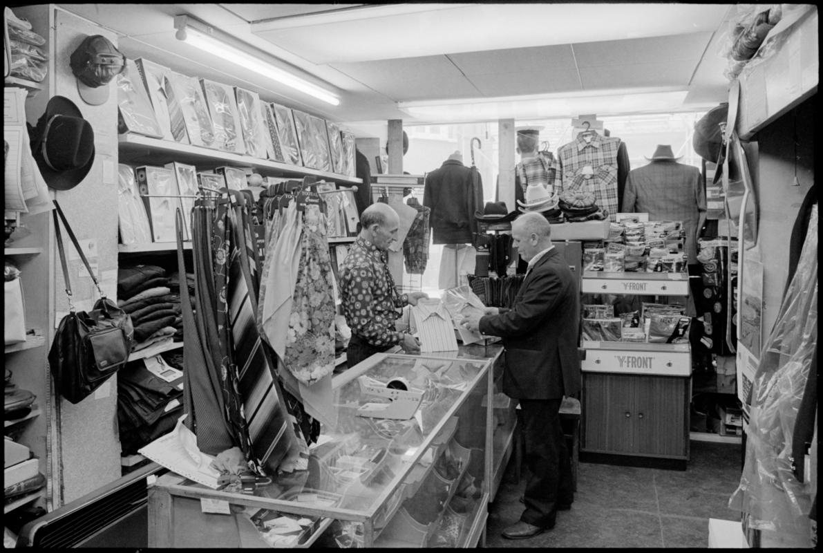 Interior view of 'Maurice Merchant Navy General Outfitter', 5 James Street, Butetown, showing the proprietor Mr M. Colpstein serving merchant seaman Mr T. Szarota. This was the last remaining outfitters in Cardiff Dockland.