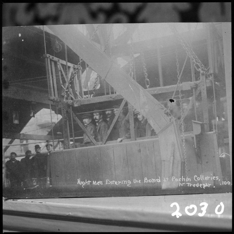 Black and white film negative of a photograph showing the 'night shift entering the bond at Pochin Colliery, Tredegar'.  'Pochin' is transcribed from original negative bag.