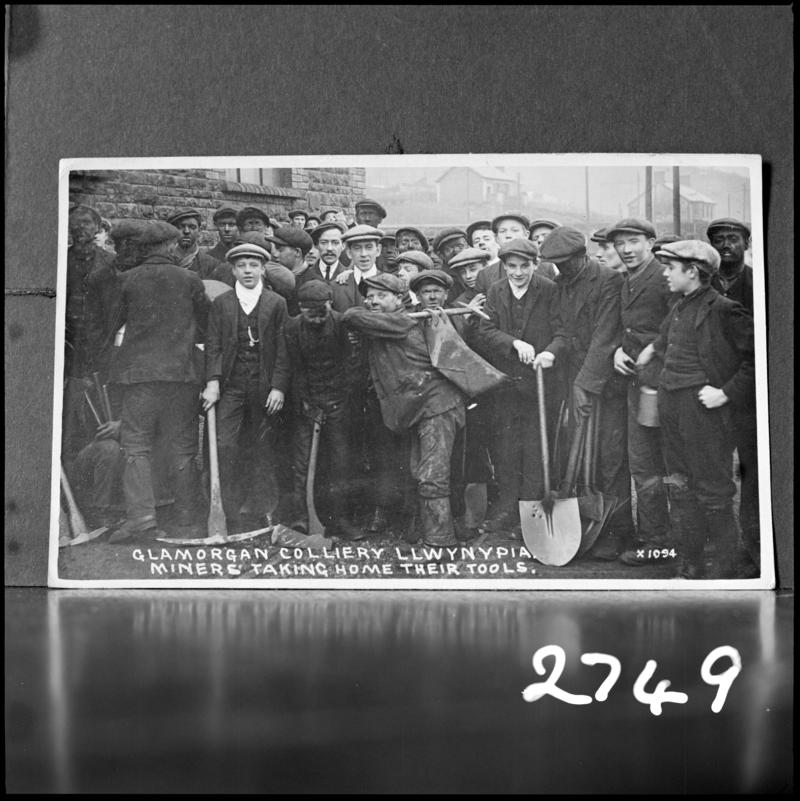 Black and white film negative of a photograph showing a group of miners at Glamorgan Colliery.  'Men at Glamorgan Colliery taking home tools' is transcribed from original negative bag.