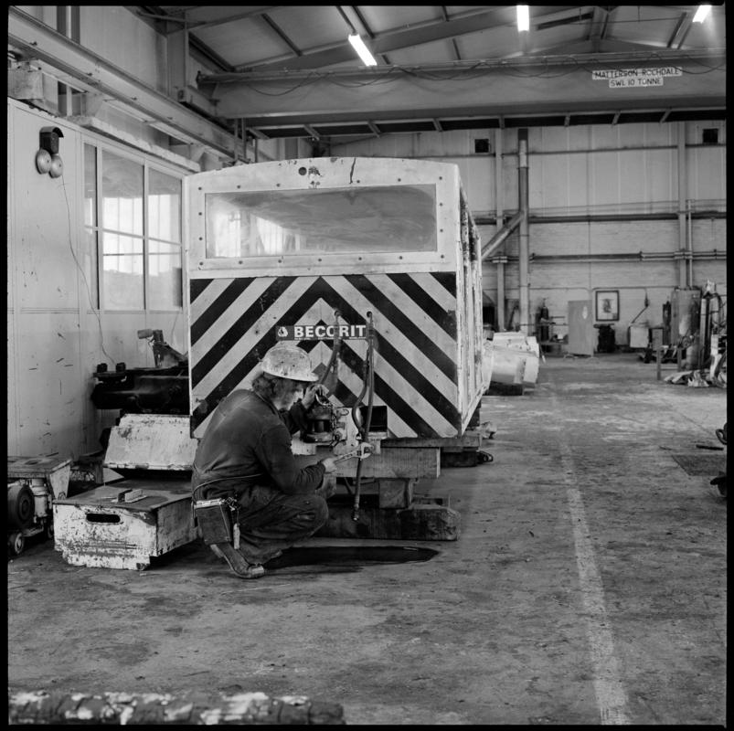 Black and white film negative showing maintenance work being carried out on a manriding train, Betws Mine.  'Betws' is transcribed from original negative bag.