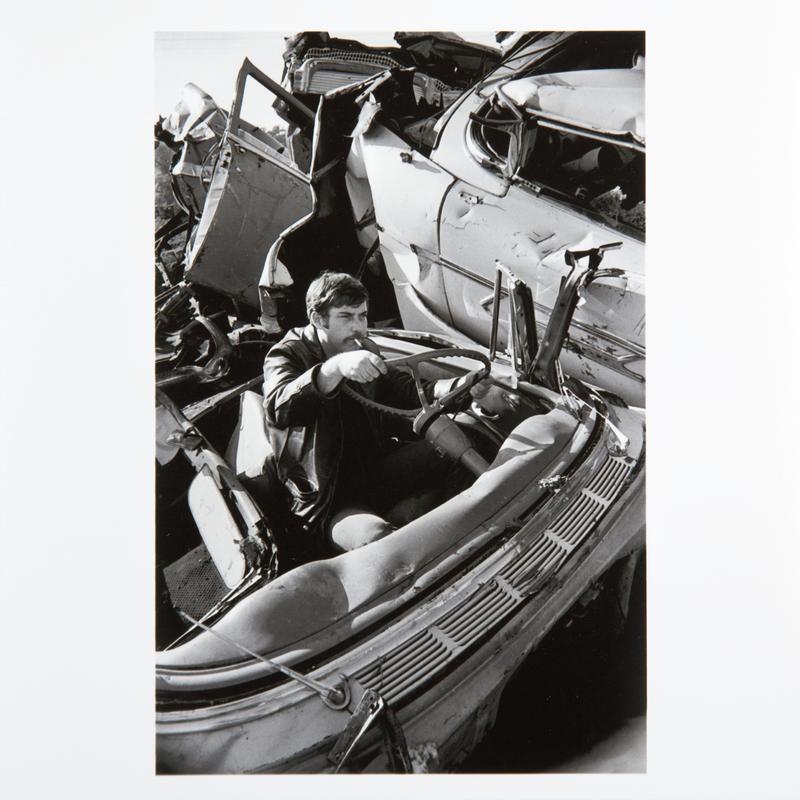 Man in a car at a junkyard. Ithaca, New York State