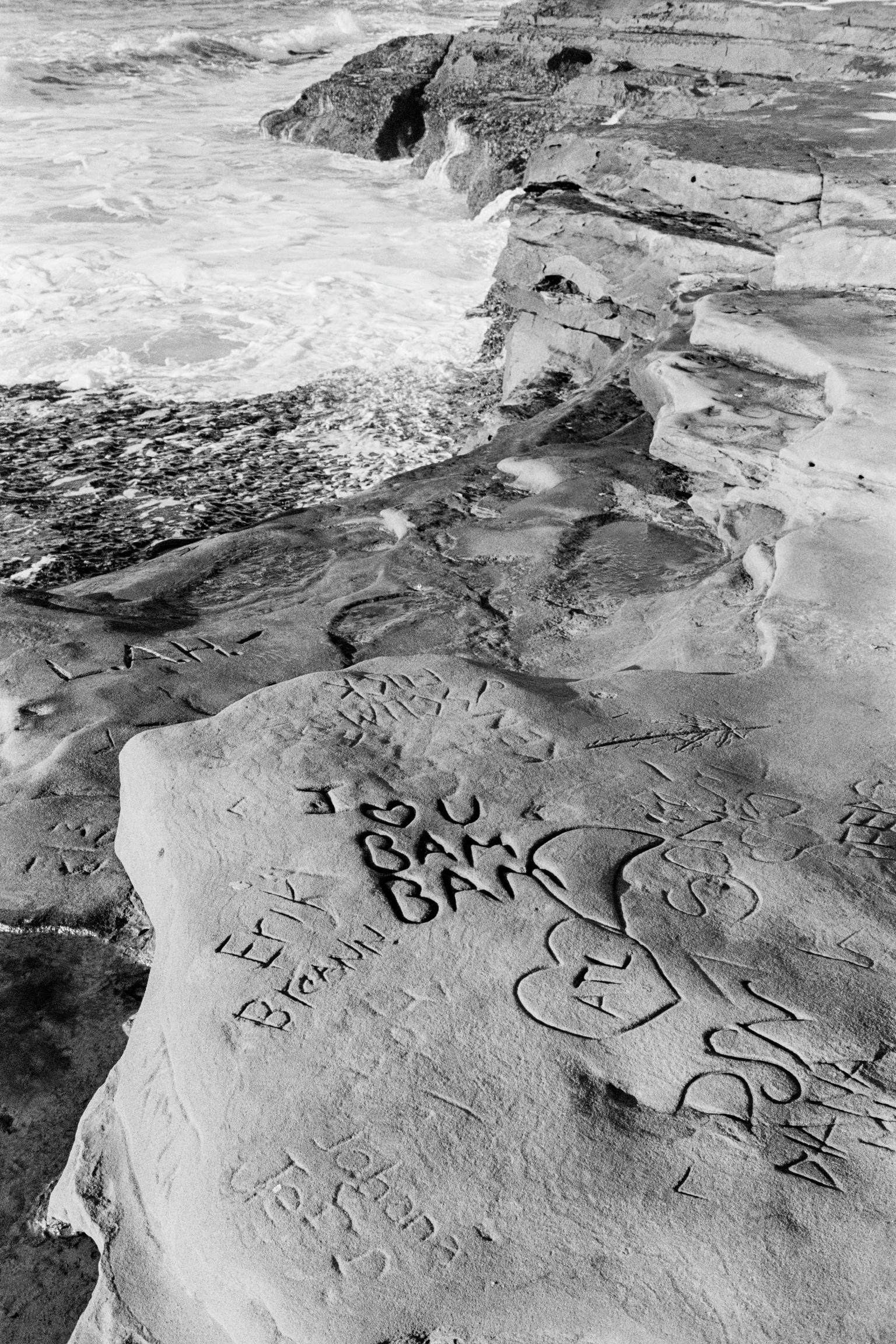 Misson Beach, grafitti carvings on beach rocks. San Diego. California, USA