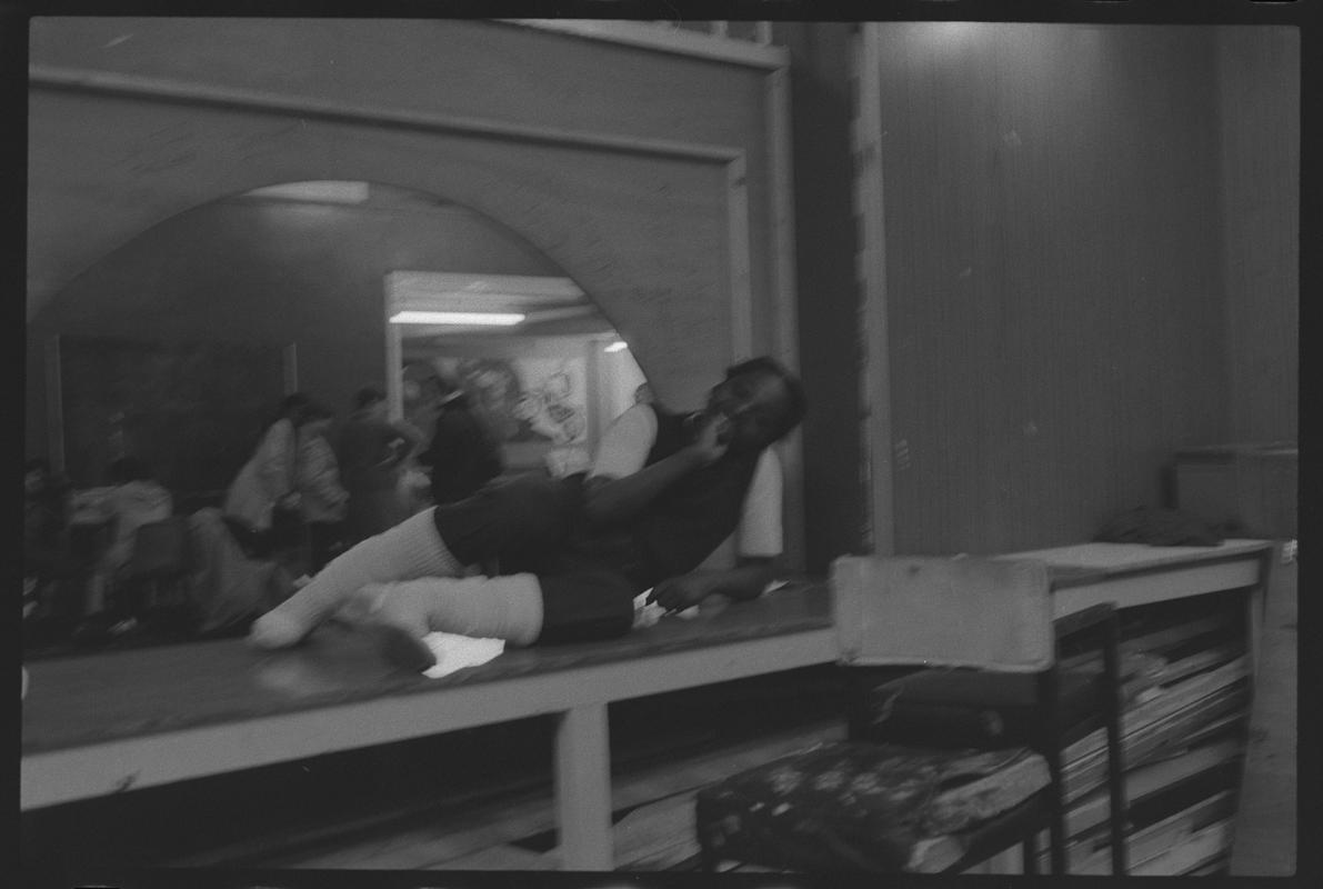 Girl sitting on counter between kitchen and hall of Butetown Youth Club.