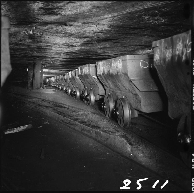 Black and white film negative showing a line of drams in the Graigola Seam, Graig Merthyr Colliery.  Note the unsupported sandstone roof.  'Graig Merthyr' is transcribed from original negative bag.