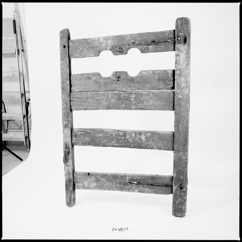 Pillory with two vertical posts united by three horizontal boards, below one fixed and one moveable horizontal board with semi-circular cut-outs, originally from village of Tregynon, Montgomeryshire.