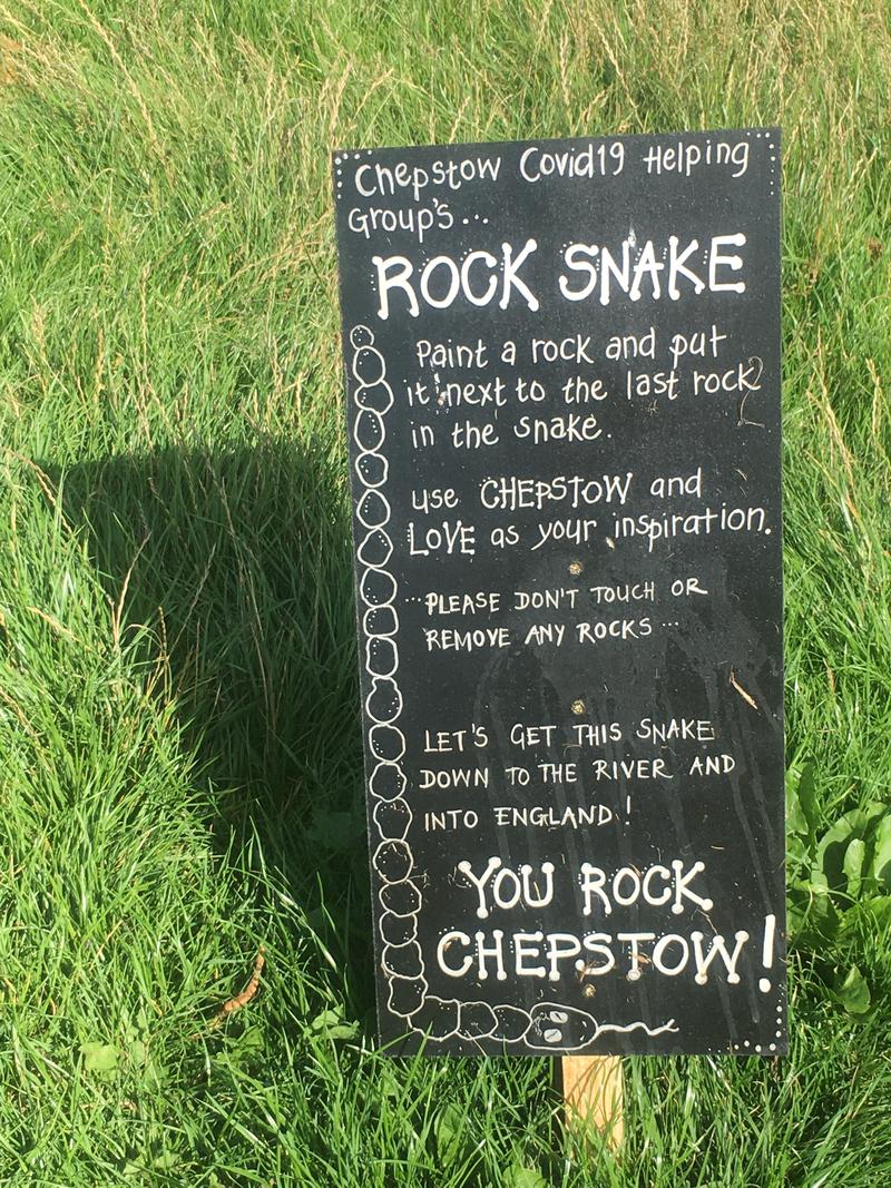 Sign near the start of the line of painted pebbles in Castle Dell, Chepstow, Monmouthshire. Reading 'Chepstow's Covid 19 Helping Group's Rock Snake Paint a rock and put it next to the last rock in the snake. Use Chepstow and Love as your inspiration. Please don't touch or remove any rocks ... Let's get this snake down to the river and into England! You Rock Chepstow!'