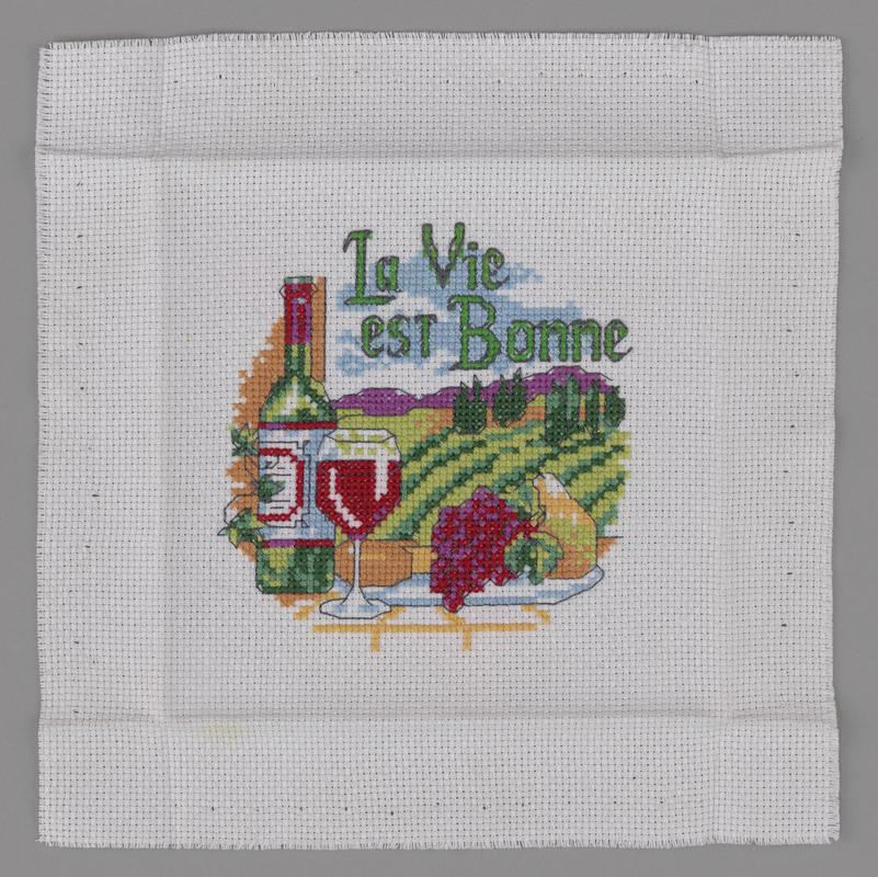 Cross stitch sampler of a bottle of red wine.