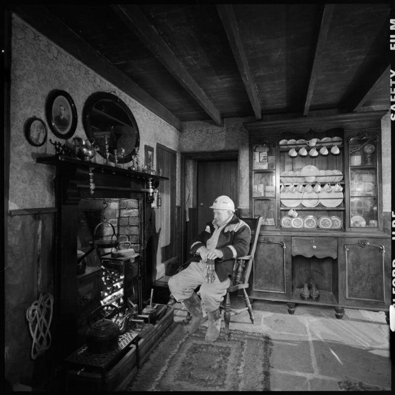 Black and white film negative showing a man inside a cottage, Blaenavon.
