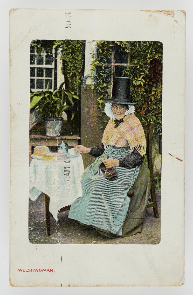 A Welsh woman at tea table with knitting on her lap.  Postmark:  Battersea S.W.