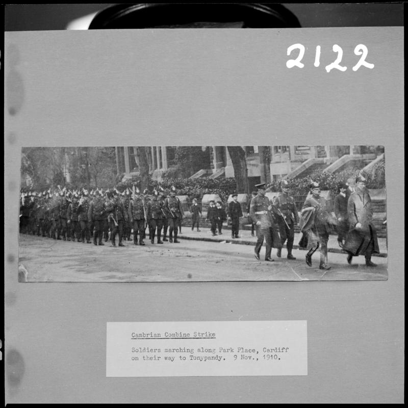 Black and white film negative of a photograph showing soldiers marching along Park Place Cardiff on their way to Tonypandy, 9 November 1910 (information taken from caption below the photograph).  '1910 lockout' is transcribed from original negative bag.