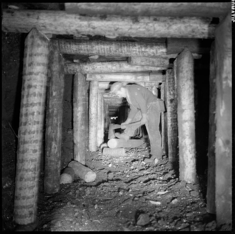 Black and white film negative showing a man preparing timber on the face, Ammanford Colliery 7 September 1976.  'Ammanford 7 Sep 1976' is transcribed from original negative bag.