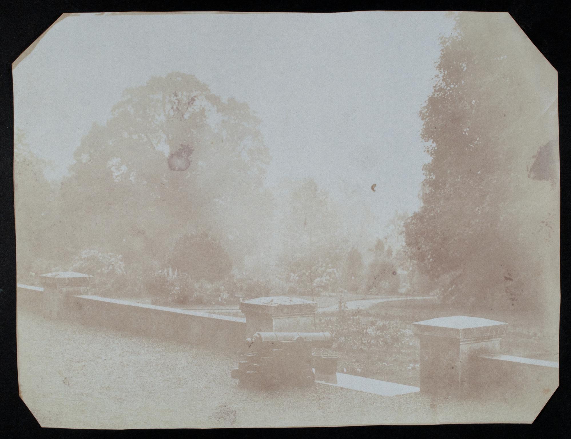 Cannon on terrace overlooking garden, photograph