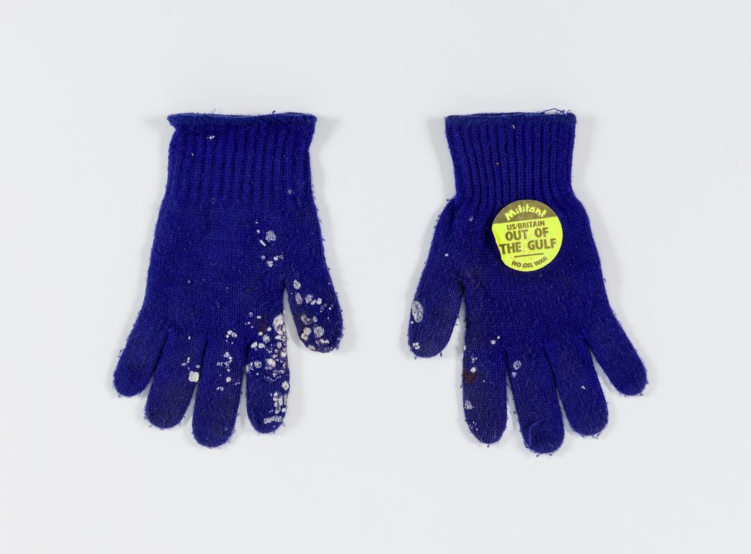 Pair of blue gloves. One has sticker saying 'Militant. US/Britain Out of the Gulf. No Oil War'. Worn by Thalia Campbell, 2003.