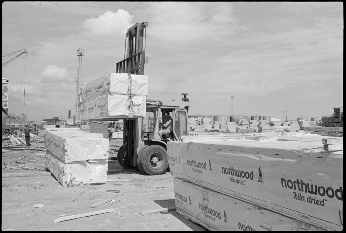 Fork lift truck raising a load of 'Northwood kiln dried' timber from the quayside, Cardiff Docks.