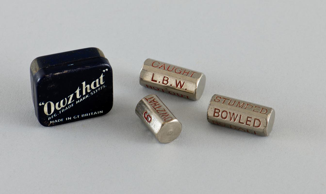Owzthat' game in original tin with spare bowling 'dice'.  Navy blue tin has brand name diagonally across centre of lid in white and contains metal bowling 'dice' and metal numerical runs 'dice'.